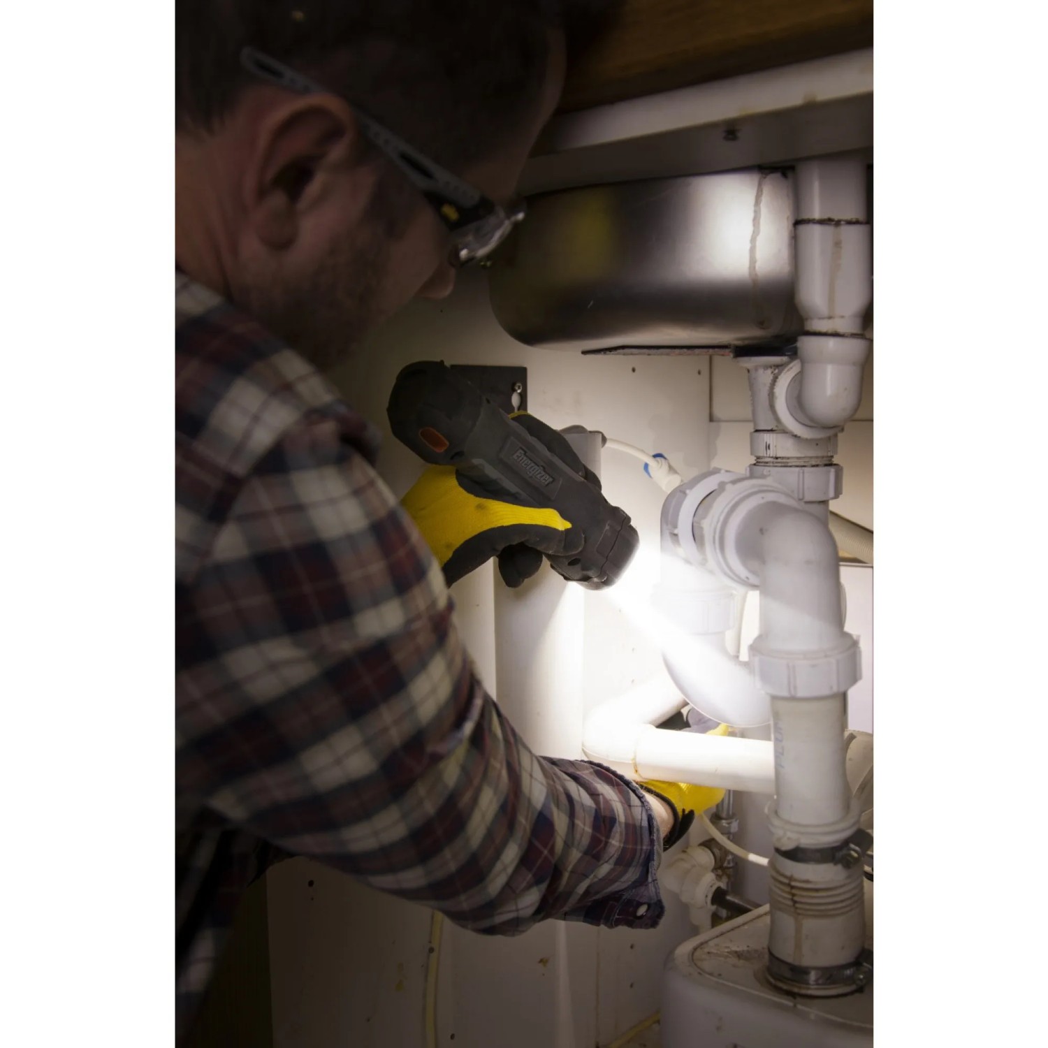 Mann nutzt Energizer Hardcase Arbeitslampe unter Spüle. Taschenlampe mit Batterien.