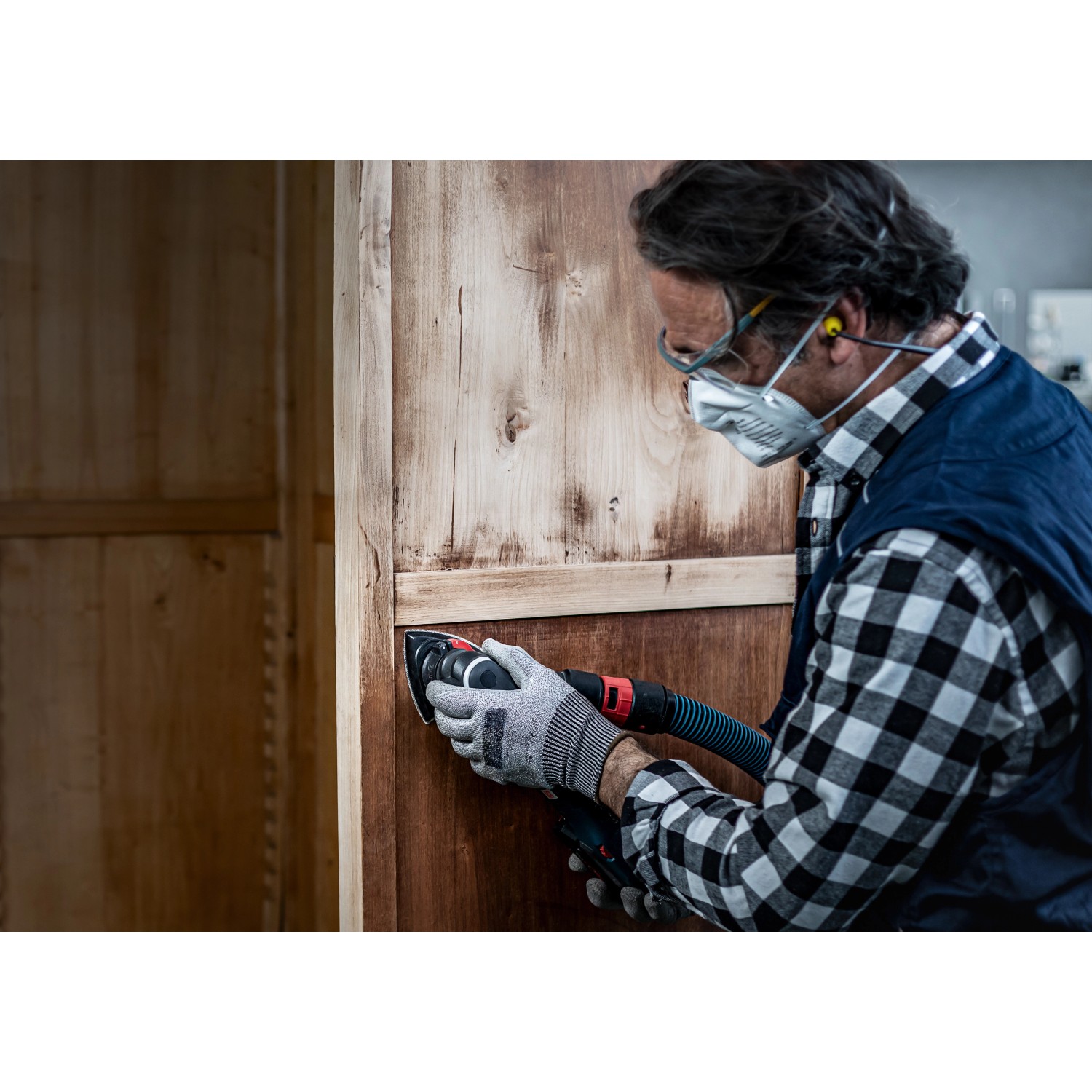 Mann schleift Holzschrank mit Bosch Deltaschleifer und Schleifblatt C470 K100.