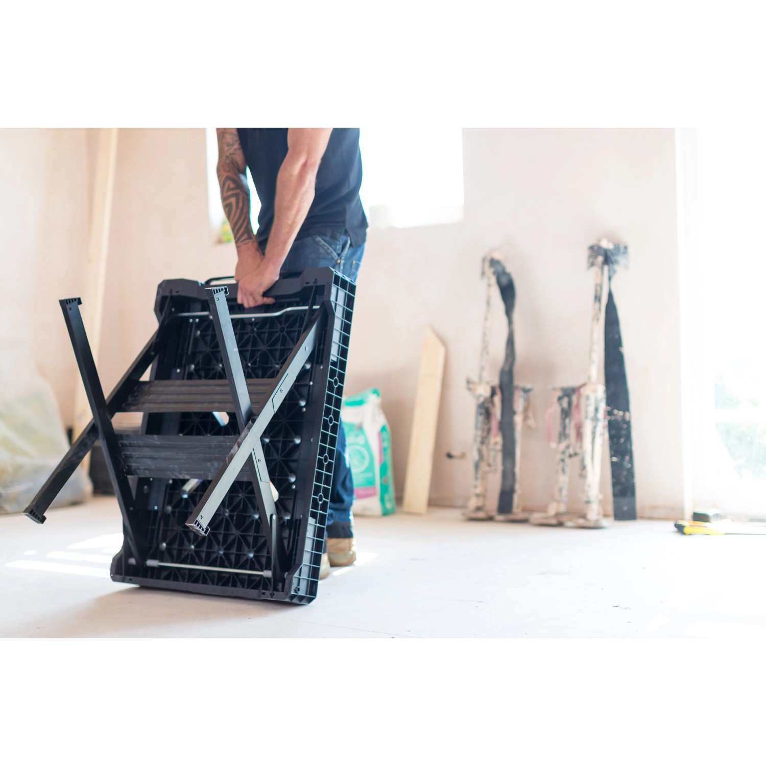 Zusammengeklappte Stanley FatMax Werkbank (85x60cm) wird von einer Person getragen.