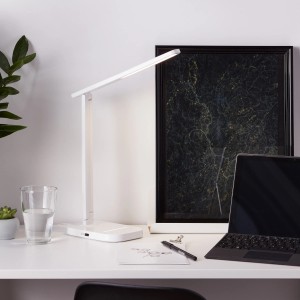 Weiße LED-Tischleuchte Vicari von Brilliant mit USB-Anschluss auf einem Schreibtisch.