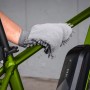 Fahrradpflege: Hand reinigt grünen Fahrradrahmen mit grauem Reinigungshandschuh.