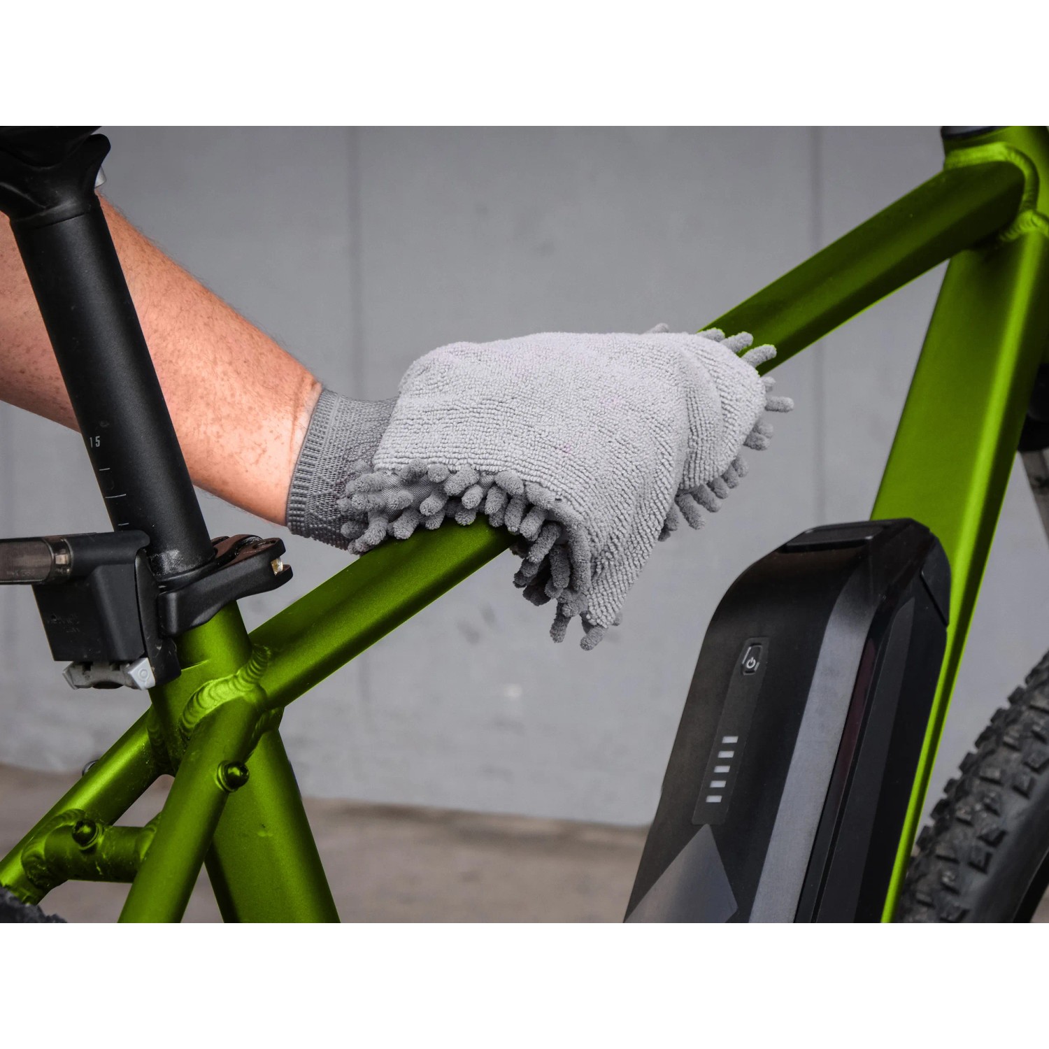 Fahrradpflege: Hand reinigt grünen Fahrradrahmen mit grauem Reinigungshandschuh.