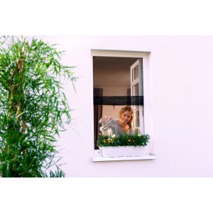 Frau gießt Blumen hinter anthrazitfarbenem tesa Fliegengitter Fenster Open/Close.