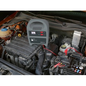 Batterie-Ladegerät 12A beim Aufladen einer Autobatterie im Motorraum.
