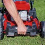 Einhell GC-PM 51/3 S HW-E Benzin-Rasenmäher in Rot, Hand am Griff auf Rasen.