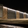 LyghtUp LED-Zaunbeleuchtung Set, anthrazit, beleuchtet einen Zaun mit Gabionen und einem Tor.
