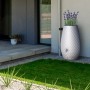Weiße Garantia Triagon Regentonne 2in1 mit Bepflanzung im Garten.