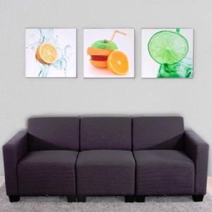 Dreiteiliges Leinwandbild mit Obstmotiven als Dekoartikel über einem Sofa.