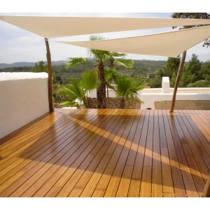 Verlegte Terrassendielen aus Holz mit Sonnensegel und Palmen im Hintergrund.