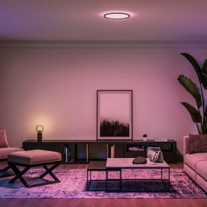 Schwarzes Philips Hue Tento LED-Panel White & Color Ambiance M, Ø 42 cm, in Wohnraum-Szene.