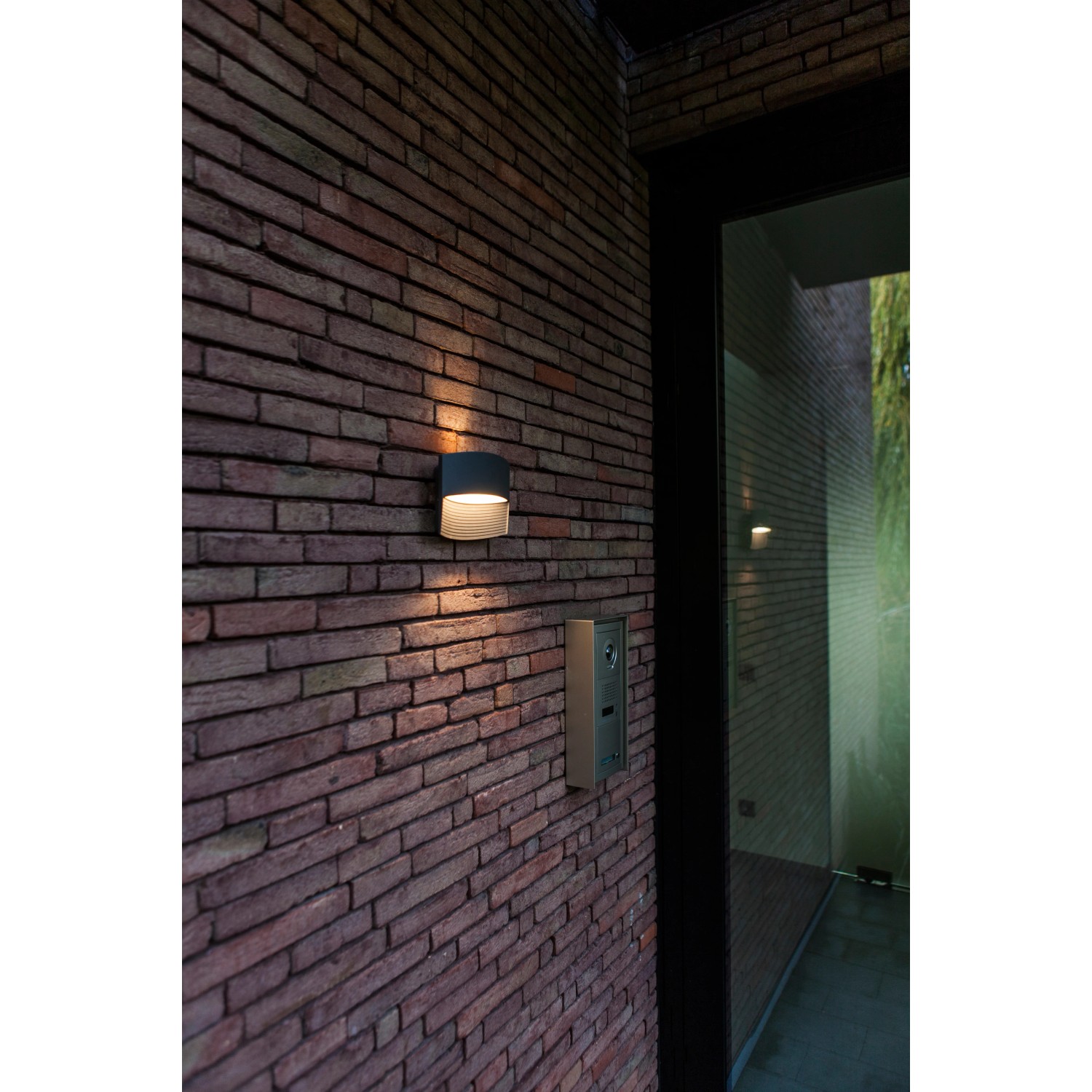 Moderne Lutec LED-Außenwandleuchte Lotus in Anthrazit mit Up & Down Lichteffekt an einer Backsteinwand.
