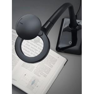 Schwarze Trio LED Lupenleuchte Lupo über einem Buch. Schreibtischlampe mit Lupe für Büro und Hobby.