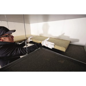Ein Arbeiter montiert eine Rockwool RAF Schallschluckplatte 30 als Mineralfaser Dämmstoff an einer Decke.