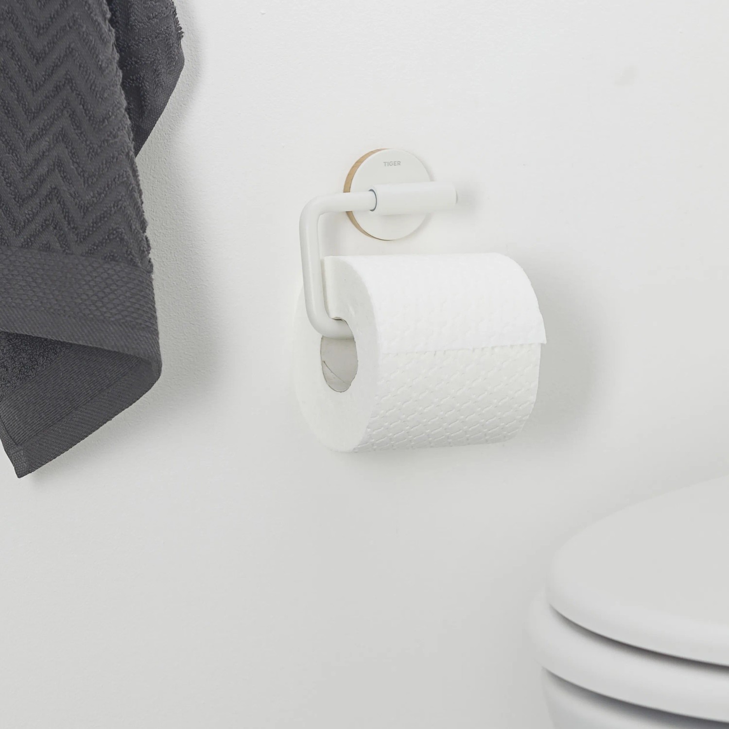 Weißer Tiger Toilettenpapierhalter Urban ohne Deckel mit Papierrolle an Wand montiert.