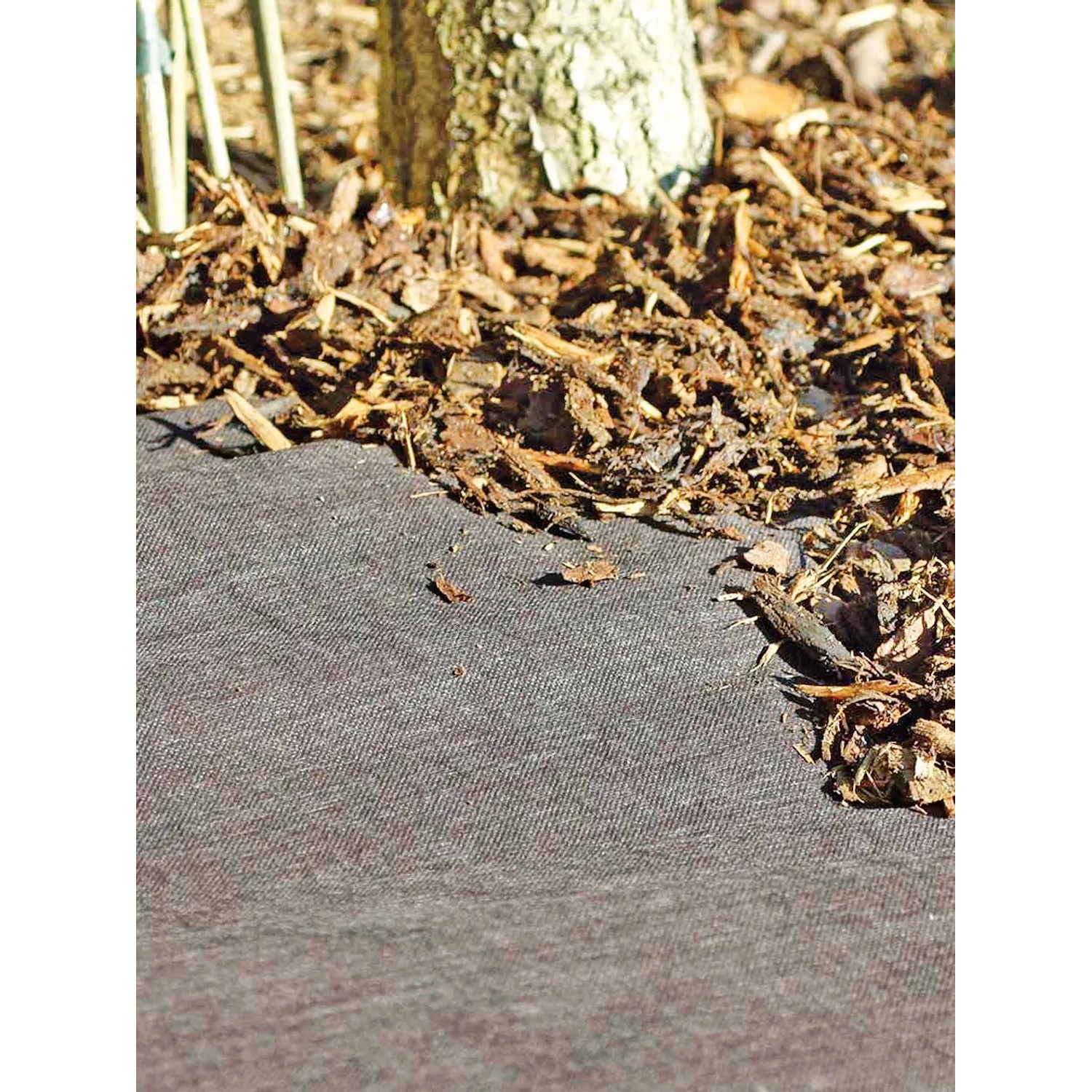 Heissner Bodenabdeckvlies Wurzel Stop, braunes Unkrautvlies unter Baumrinde.