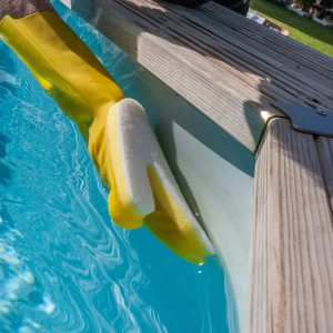 Gelber Gre Handschuh mit Schwamm zur Poolreinigung an der Wasserlinie.