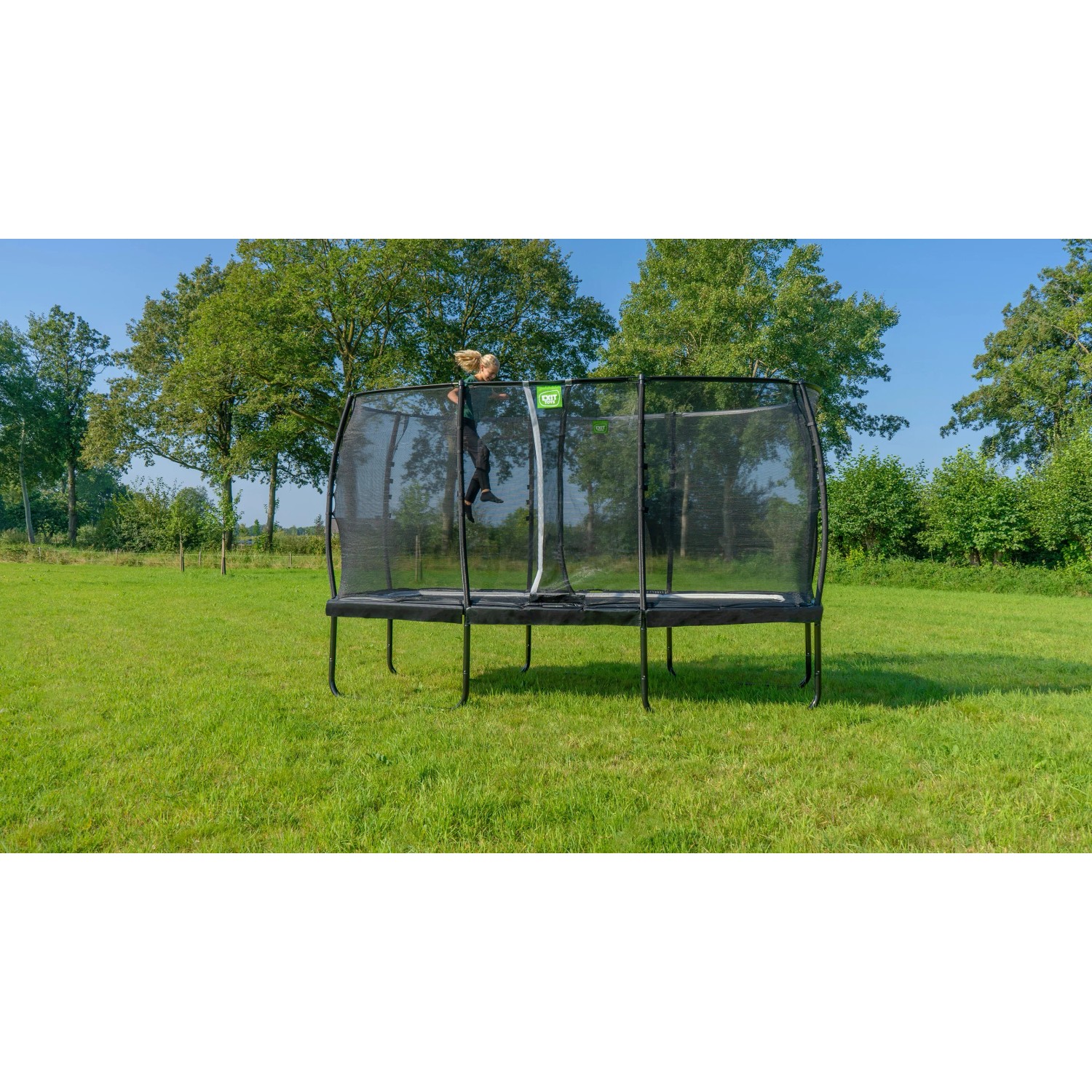 Rechteckiges, grünes Gartentrampolin mit Sicherheitsnetz und Person beim Klettern.