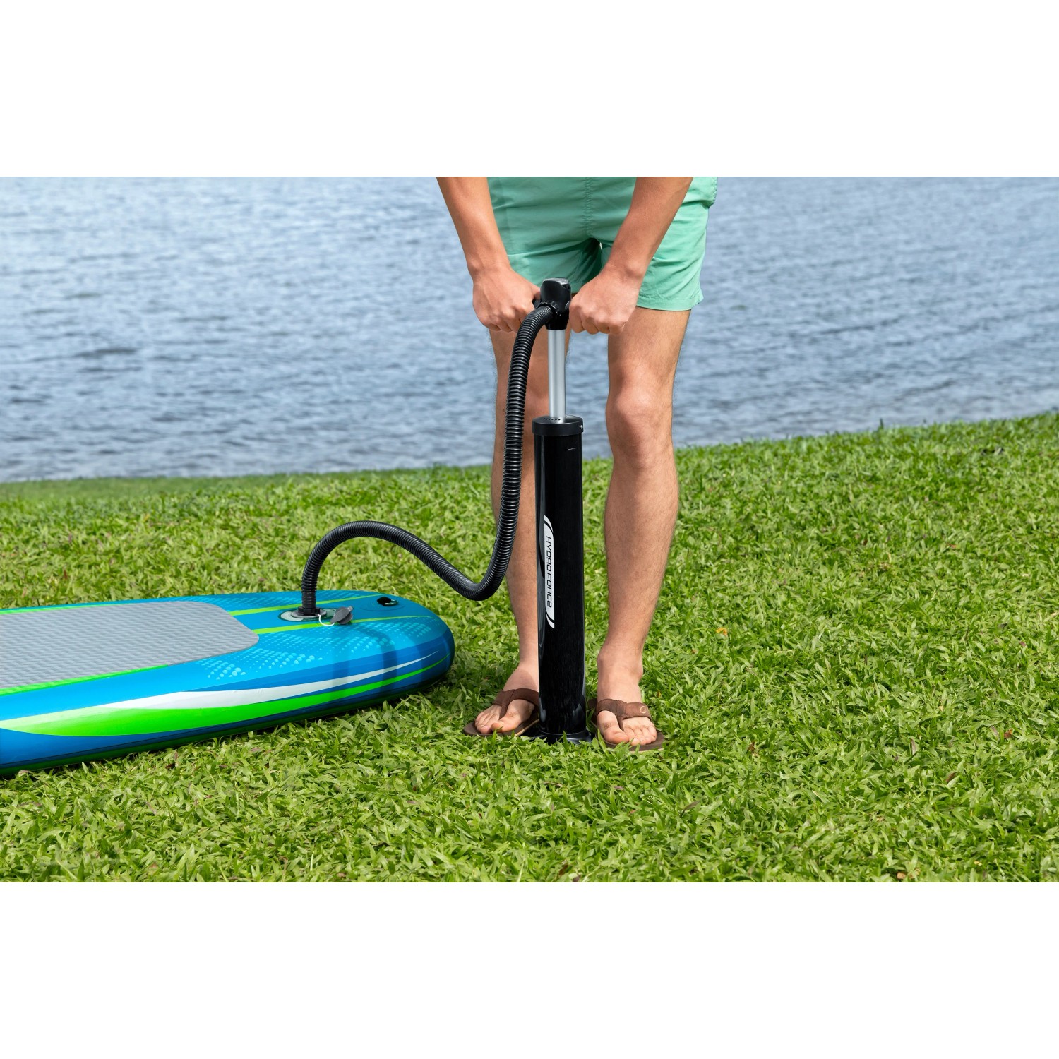 Aufpumpen des Bestway SUP Aqua Journey mit Pumpe. Das Board ist blau-grün und liegt auf einer Wiese.