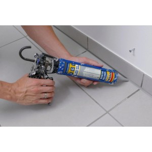 Hände dichten mit Soudal Sanitär Silikon Grau eine Fuge zwischen hellgrauen Fliesen und weißer Wand ab.