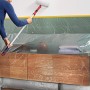 Frau streicht Wand mit Tesa Abdeckfolie Easy Cover Perfect+ L, Möbel abgedeckt.