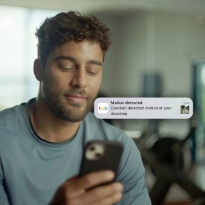 Mann sieht Benachrichtigung der Philips Hue Türklingelkamera auf dem Smartphone.