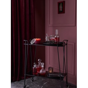 Bordeaux-farbene Duftkerze Midnight Mystery mit silbernem Deckel auf einem Servierwagen.