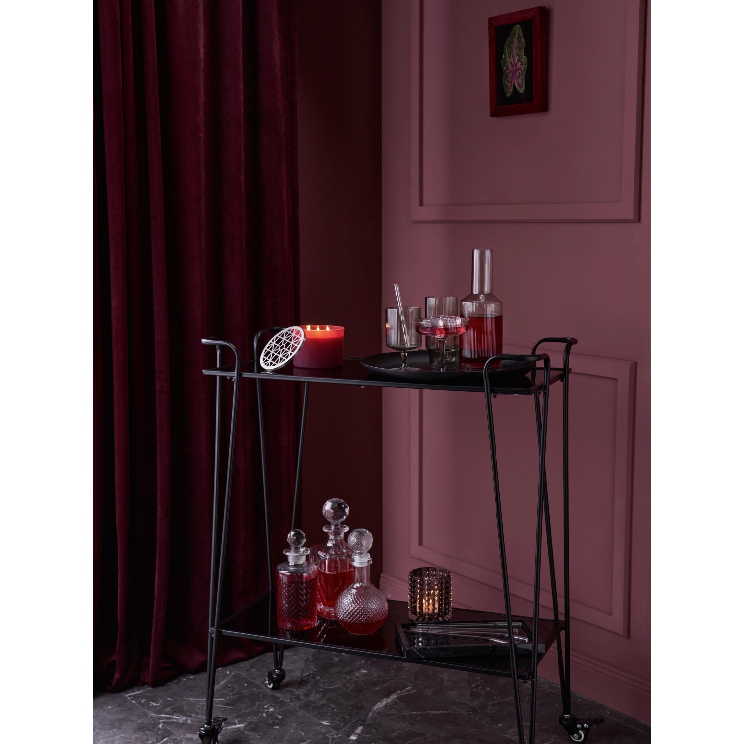 Bordeaux-farbene Duftkerze Midnight Mystery mit silbernem Deckel auf einem Servierwagen.