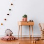 Kinderzimmer mit weißer Uni-Tapete, Holztisch und Deko-Elementen.