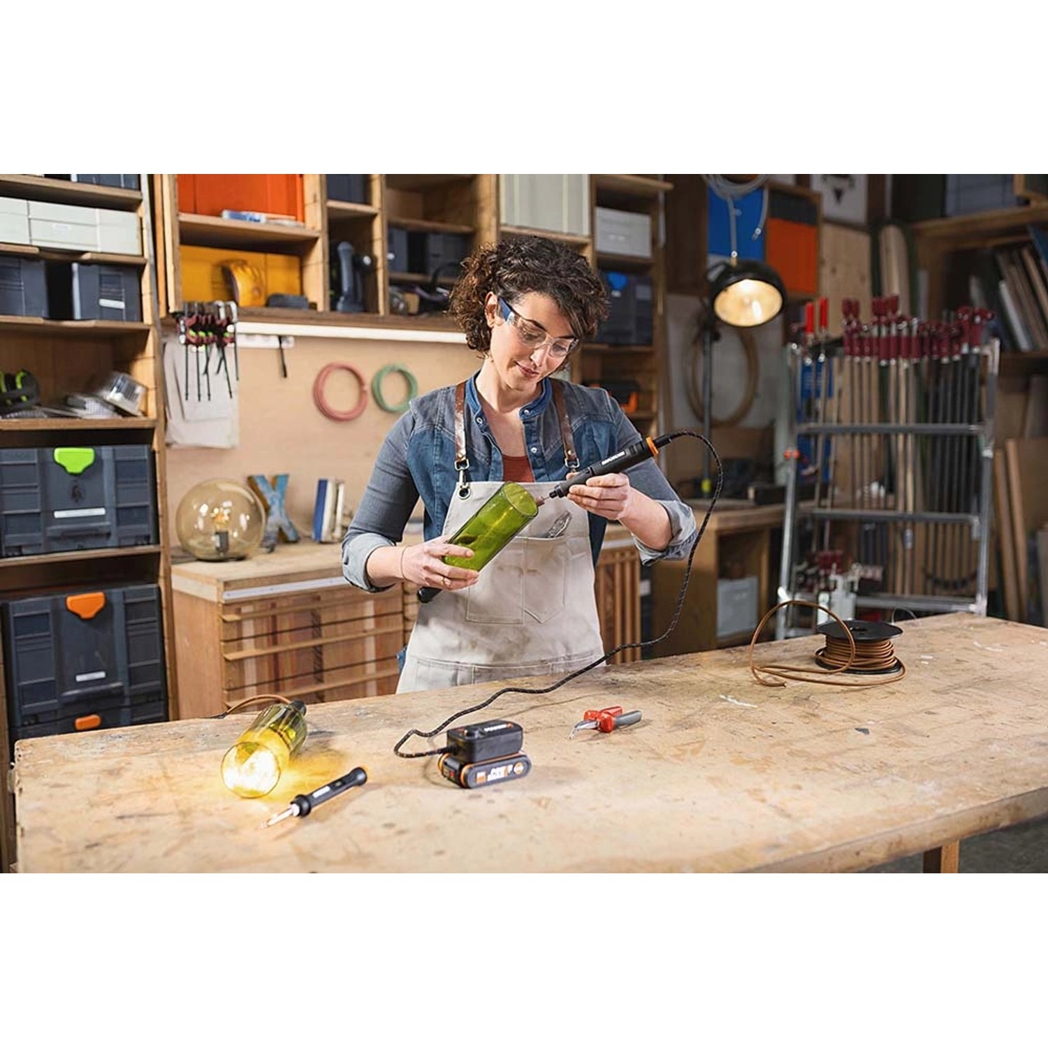 Frau arbeitet mit Worx MakerX Multifunktionstool an einer Glasflasche. Inkl. Akku und HubX.