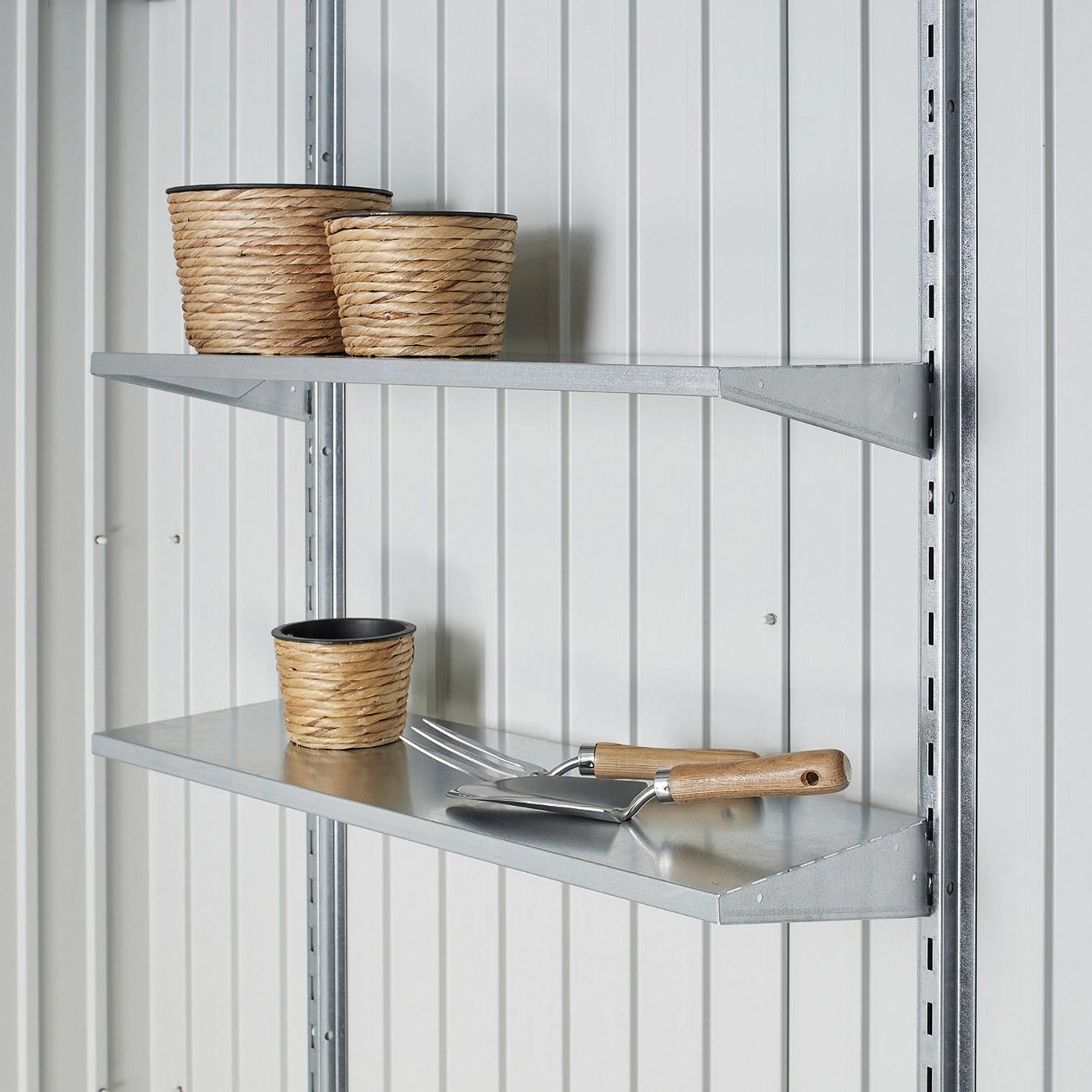 Regalsystem im Biohort Gerätehaus HighLine: Metallregale mit Pflanzgefäßen und Gartengeräten.
