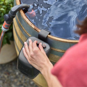 Gardena Akku-Regenfasspumpe 2400 ComfortAutomatic am Regenfass mit Hand an Bedienelementen.