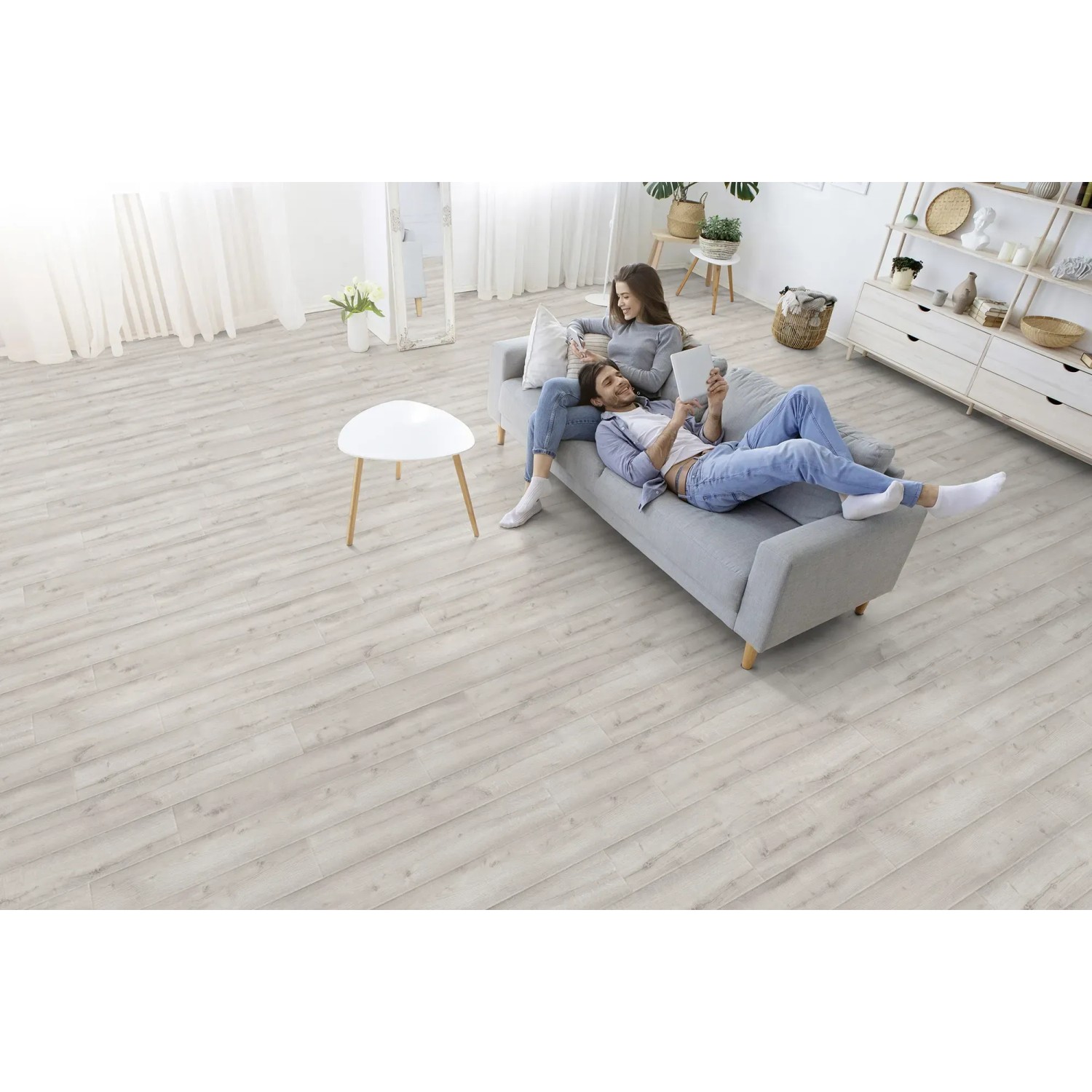 Heller Wohnraum mit Kaindl Laminat Eiche Historic Arctic, Paar auf Sofa.