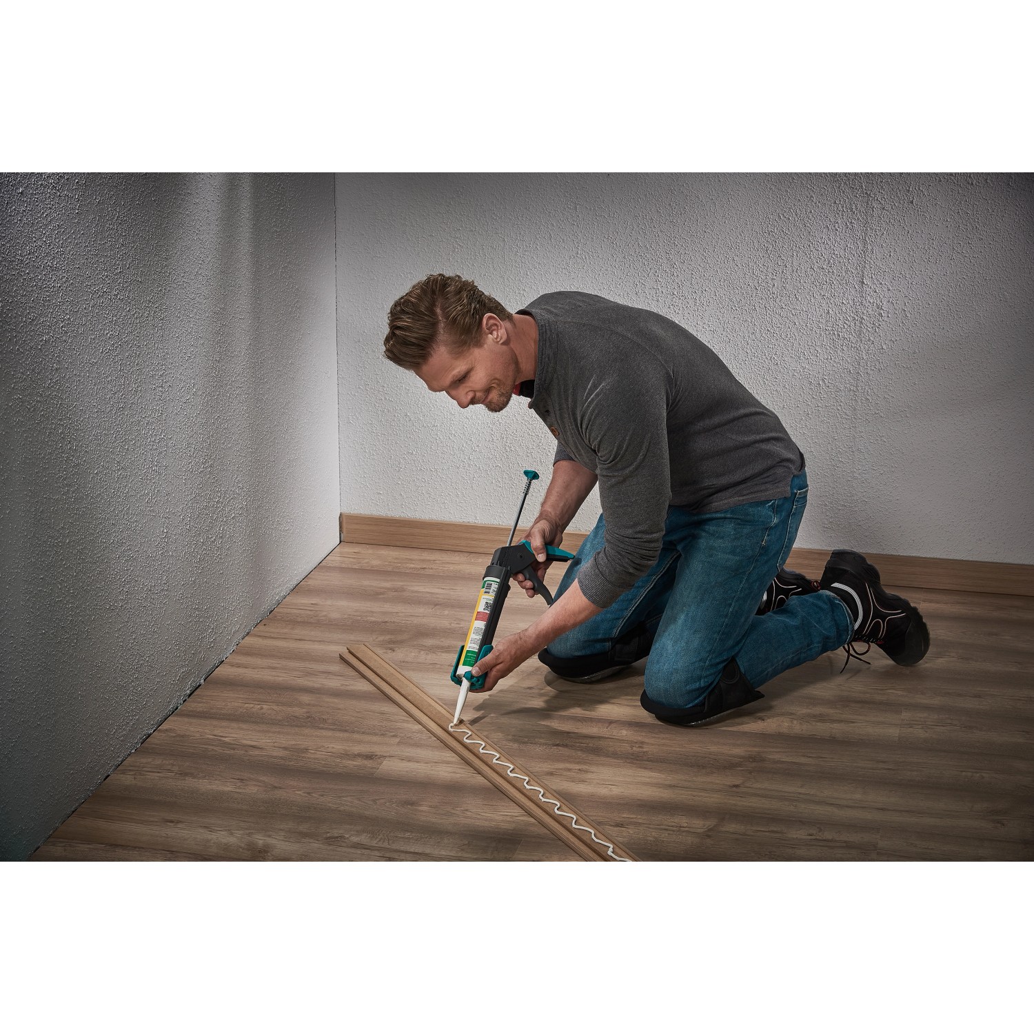 Mann verklebt Sockelleiste mit Kartuschenpresse aus dem wolfcraft Montage-Set.