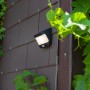 Moderne, schwarze Lutec LED Solar-Wandleuchte mit Bewegungsmelder an einer Hauswand.