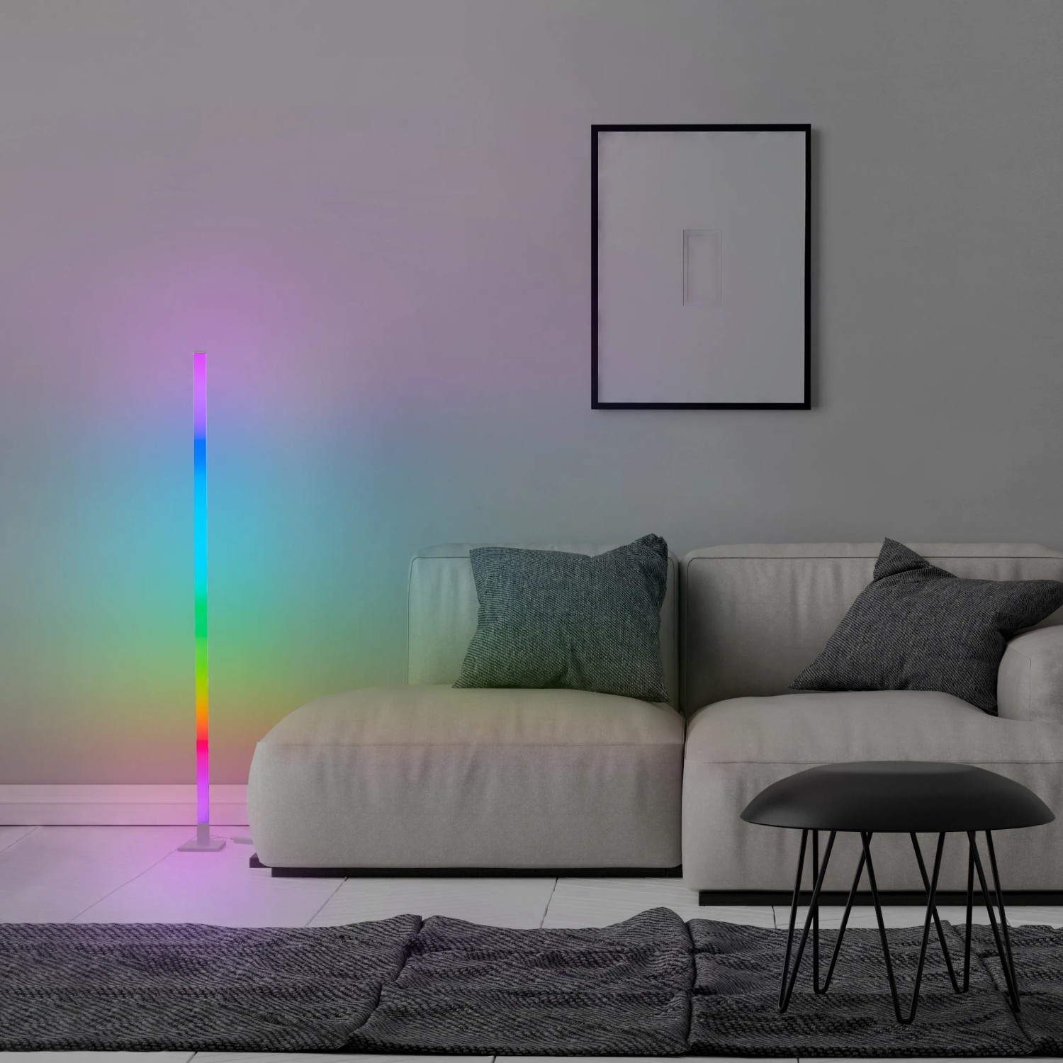 Moderne LED-Stehlampe Neele RGB+CCT, weiß, im Wohnzimmer mit Sofa und Bild.