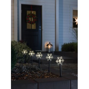 Fünf warmweiße LED-Schneeflocken-Spießleuchten beleuchten einen Gartenweg. Festliche Außen-Weihnachtsdeko.