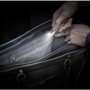 Energizer Speziallampe als Schlüsselanhänger leuchtet in eine schwarze Handtasche.