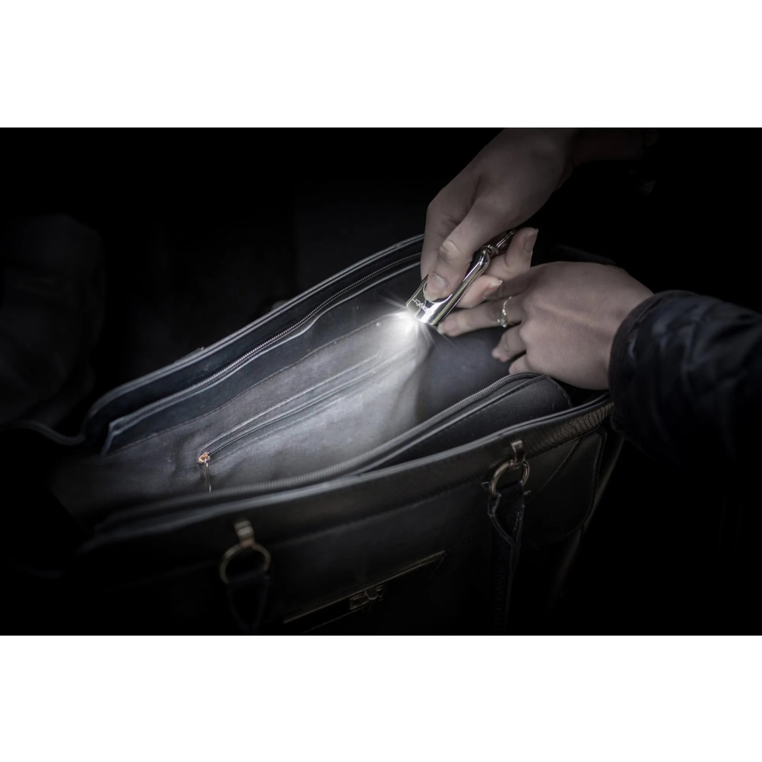Energizer Speziallampe als Schlüsselanhänger leuchtet in eine schwarze Handtasche.