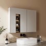 Weißer Emke Spiegelschrank 85x65 cm mit 2 doppelseitigen Spiegeltüren und beleuchteten offenen Regalen im Bad.