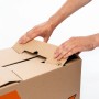 Hände falten OBI Umzugskarton M (60 l, 30 kg) zusammen. Beschriftungsfelder sichtbar.