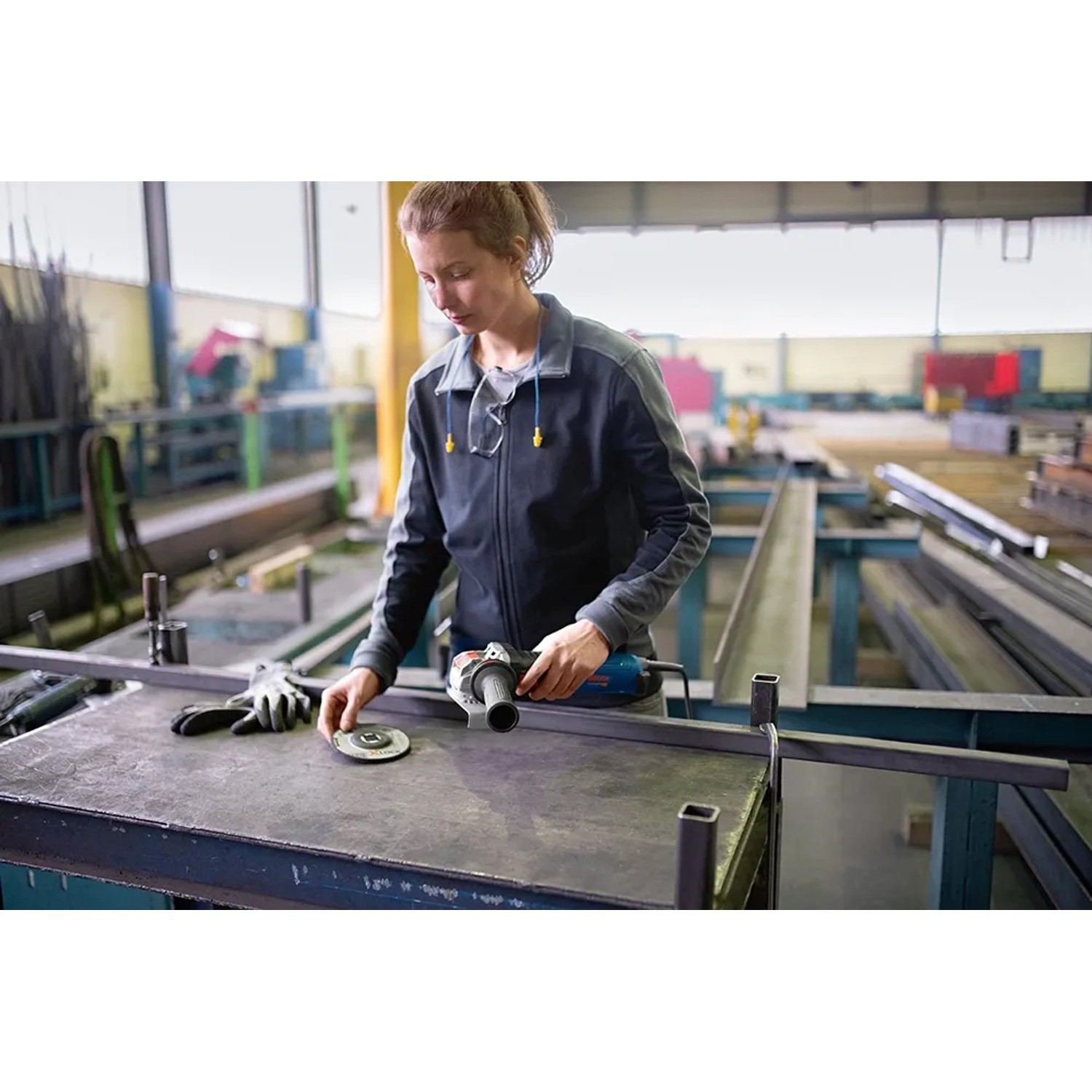 Frau arbeitet mit Bosch Professional GWX 14-125 S X-Lock Winkelschleifer in Werkstatt.