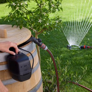 Gardena Akku-Regenfasspumpe 2600 Comfort im Einsatz mit Regner im Garten.