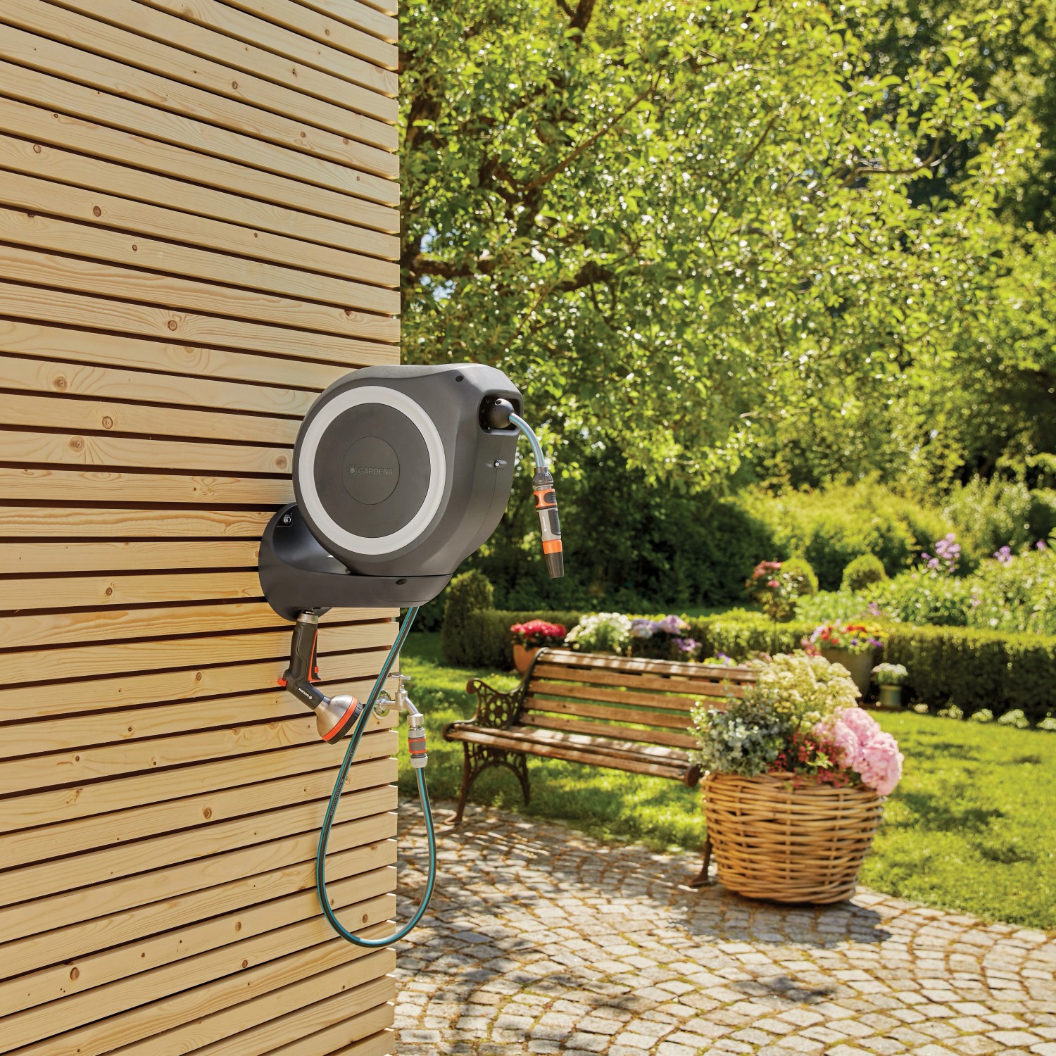 Gardena Wand-Schlauchbox RollUp S mit 15m Schlauch an Holzwand im Garten.