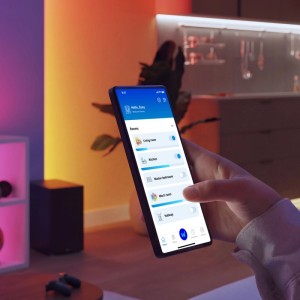 Hand steuert Philips Smart Leuchtmittel mit WiZ App auf Smartphone. Zeigt farbiges und weißes Licht im Raum.