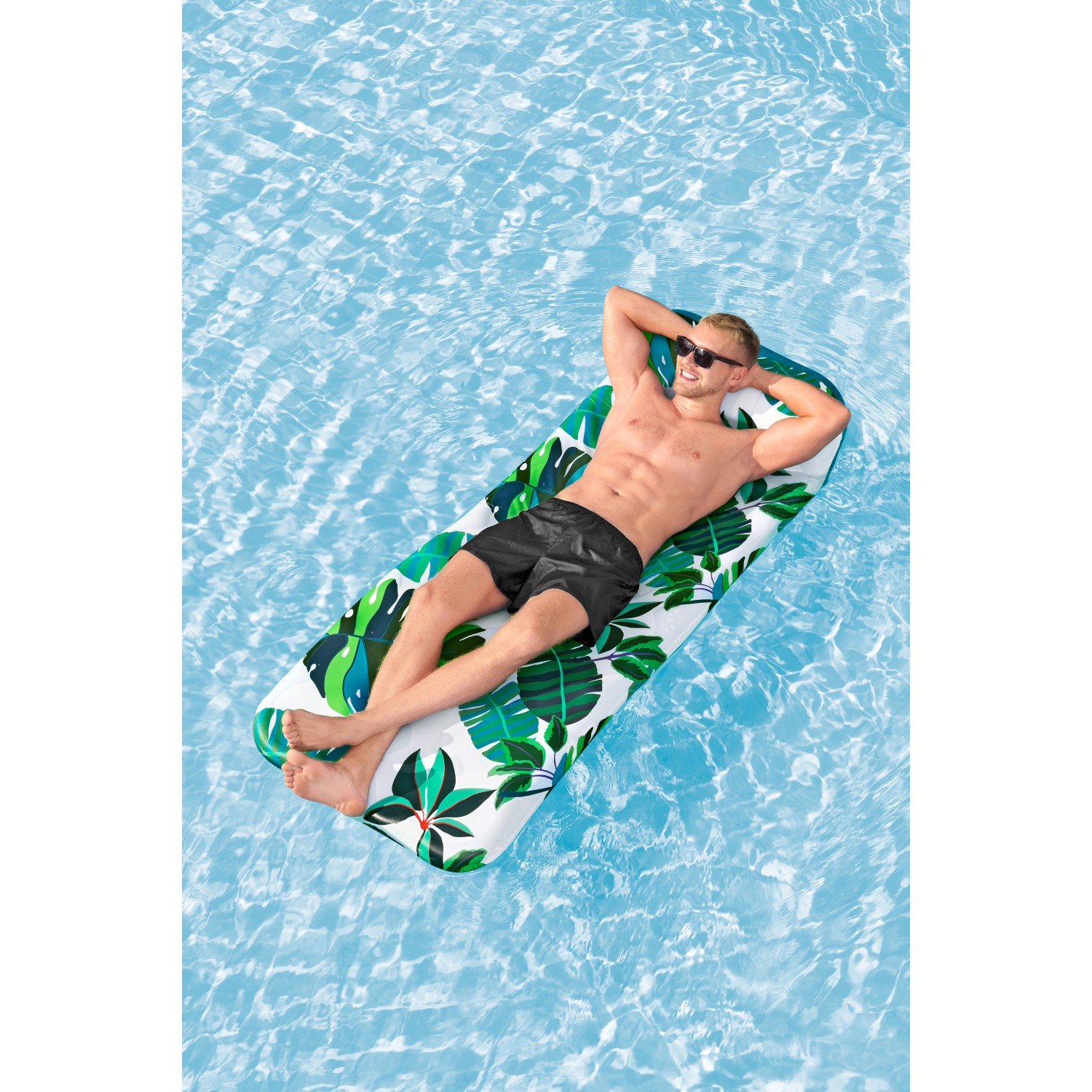 Mann entspannt auf Bestway Luftmatratze Blissfull Drifter mit tropischem Muster im Pool.