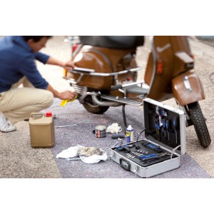 Mann reinigt Roller auf LUX Abdeckvlies. Werkzeugkoffer und Ölkanister stehen bereit.