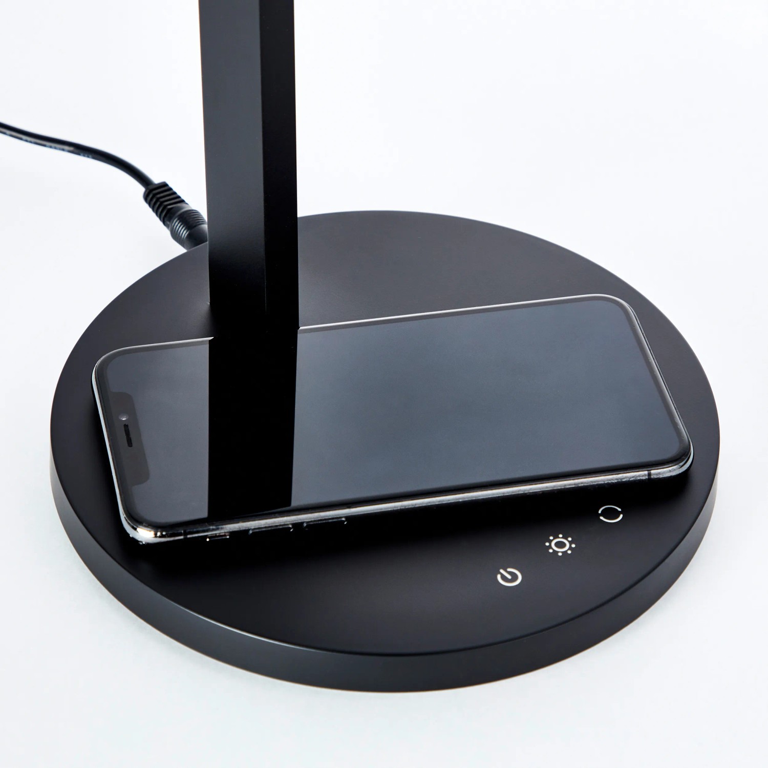 Schwarze LED-Schreibtischleuchte Devy mit induktiver Ladefläche für Smartphones.