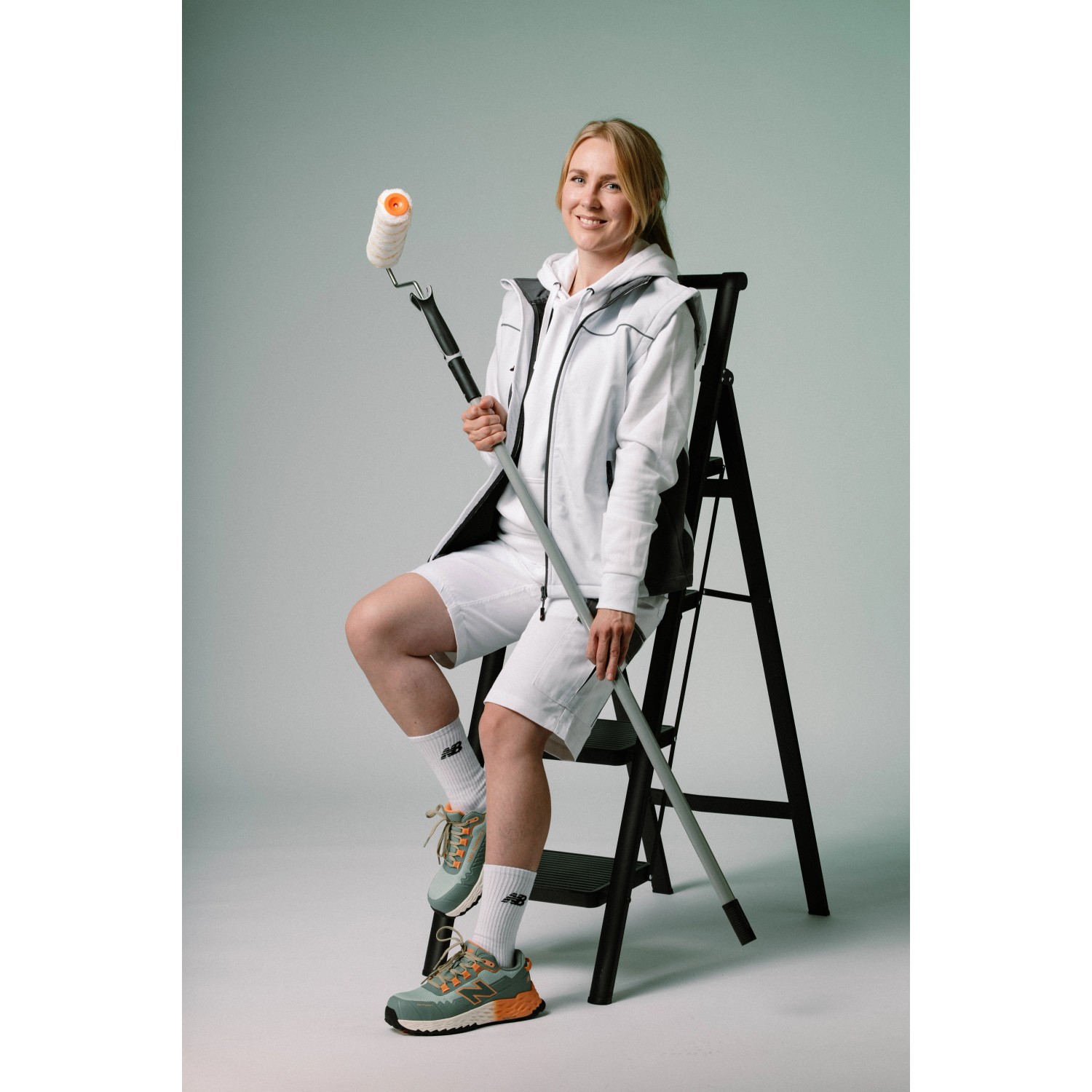 Frau mit New Balance Sicherheitsschuhen Cremorne Aqua-Pumpkin auf einer Leiter mit Farbroller.