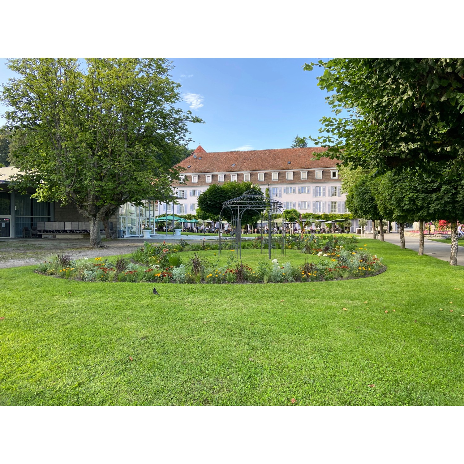 Eleo Pavillon Milano, pulverbeschichtet, schwarz, im Garten mit Blumenbeet und Rasenfläche.