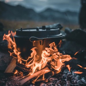 Schwarzer Petromax Dutch Oven FT9-T (7,5 l) mit planem Boden auf offenem Feuer. Ideal zum Kochen im Freien.